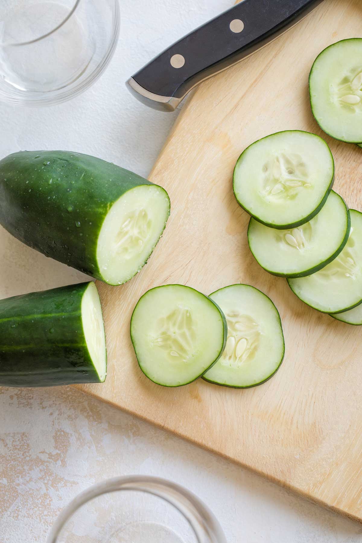 Closeup of cucumber slices on a cutting board.